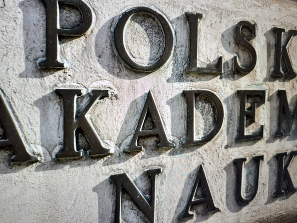 Zbliżenie na napis z wmurowanym w ścianę mosiężnych liter: Polska Akademia Nauk